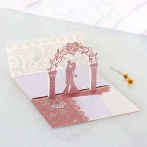 Detail of pink glitter laser-cut wedding invitation featuring a romantic 3D archway