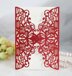 Macro shot of glitter red laser-cut wedding invitation with elegant hollow pattern