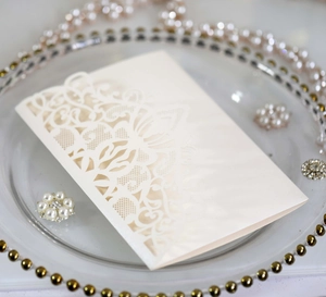 Detailed laser-cut pattern on ivory pearlescent wedding invitation card with elegant motif