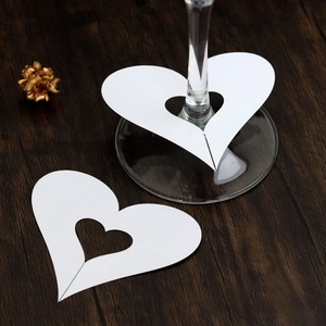Detailed close-up of hollow white heart-shaped paper place cards for wine glass decoration