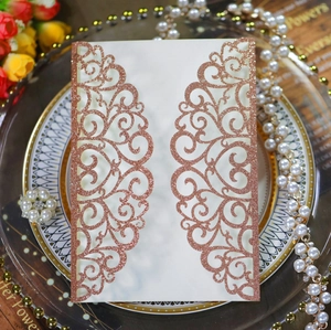 Detail of laser-cut wedding invitation with rose gold glitter and floral lace patterns