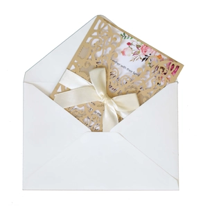 Detail of laser-cut pink invitation cover with floral insert and satin ribbon bow