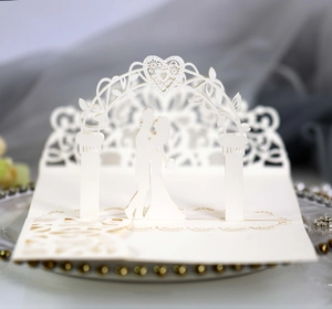 Detail of laser-cut 3D wedding invitation featuring a romantic couple under a floral arch