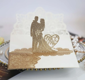 Dettaglio dell'invito di nozze intagliato al laser con glitter oro e sagoma di Mr & Mrs