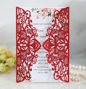 Detail of laser-cut red glitter wedding invitation with floral insert and elegant pearls