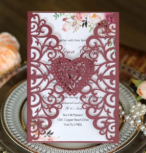 Detail view of burgundy laser-cut heart invitation card with floral insert on a tray