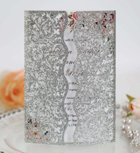 Detail of silver glitter laser-cut wedding invitation with floral insert card and vine patterns