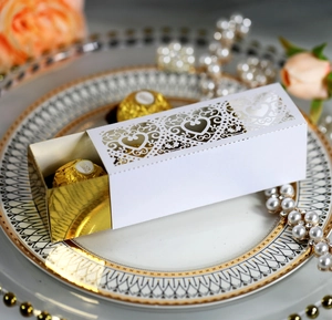 Detail of white laser-cut heart candy box with gold insert on decorative plate