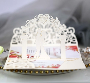 Detail of 3D laser-cut wedding invitation showing a couple silhouette and heart arch