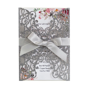 Macro detail of laser cut glitter wedding invitation with silver bow and floral inlay