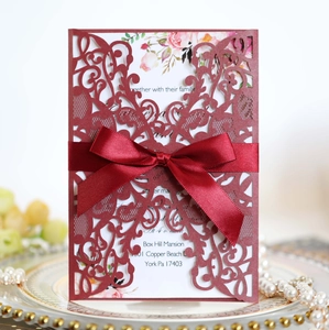 Detail of burgundy laser cut wedding invitation with ribbon and floral insert card