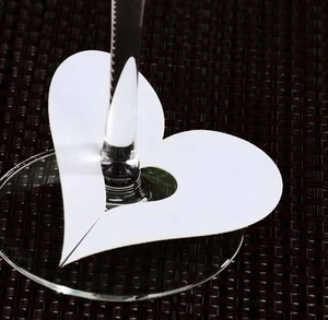 Macro shot of heart-shaped white paper place card with laser cut for wine glass stem