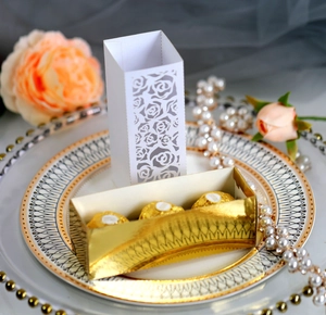 Laser-cut floral wedding favor boxes in white and gold with chocolate tray display
