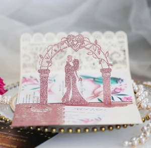 Detail of 3D laser cut pink glitter wedding invitation with couple silhouette and floral arch