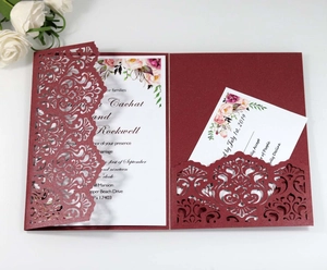 Detail of laser-cut burgundy invitation set with floral card and RSVP card on grey surface