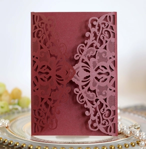 Macro view of burgundy laser-cut invitation cover with intricate floral patterns