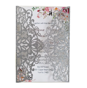 Macro detail of silver glitter laser-cut invitation card with floral watercolor inner page