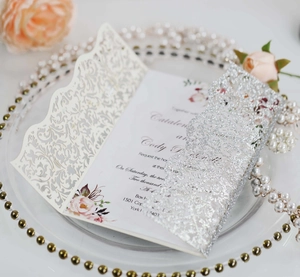 Macro detail of laser-cut floral pattern on wedding invitation with silver glitter finish
