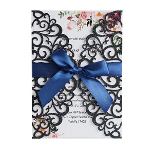 Detailed laser-cut navy blue glitter wedding invitation with elegant ribbon and floral inner card