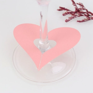 Close-up of pink heart-shaped laser-cut paper wine glass card for wedding table decor