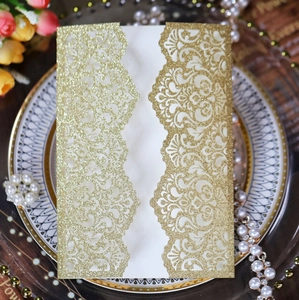 Close-up of laser-cut glitter gold wedding invitation with elegant vine patterns