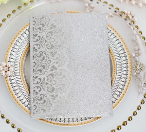 Detail of silver glitter laser-cut invitation cover on a luxury decorative plate