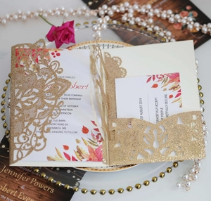 Gros plan d'invitations de mariage découpées au laser avec paillettes dorées et feuilles
