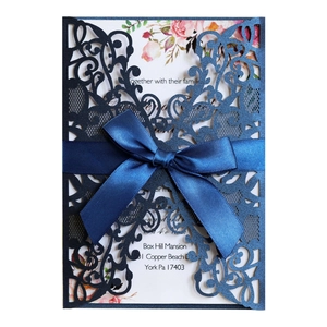 Navy laser-cut wedding invitation with blue satin bow and floral inner page