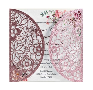 Close-up of laser-cut rose gold glitter wedding invitation with floral hollow patterns