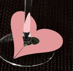 Close-up of pink heart-shaped laser cut paper card for wine glass stem decoration