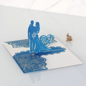 Dettaglio dell'invito di nozze 3D tagliato al laser con glitter blu e sagoma Mr & Mrs