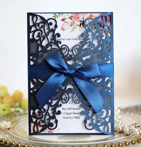 Detailed laser-cut navy blue wedding invitation with ribbon and floral insert card