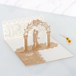 Detail of 3D laser cut wedding card with gold glitter couple silhouette and lace edges