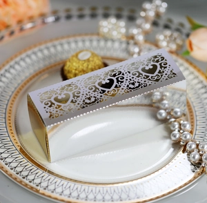Detail of silver laser-cut heart pattern wedding favor box with pearl and flower accents