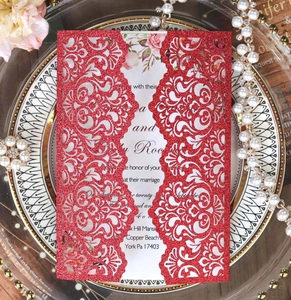 Close-up of red glitter laser-cut wedding invitation with elegant hollow-out floral pattern