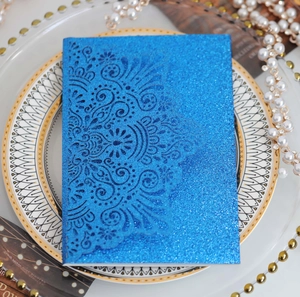 Dettaglio del motivo mandala tagliato al laser su carta glitterata blu per inviti di nozze