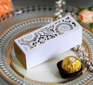 Detailed view of laser-cut wedding candy box with elegant floral patterns on a gold base
