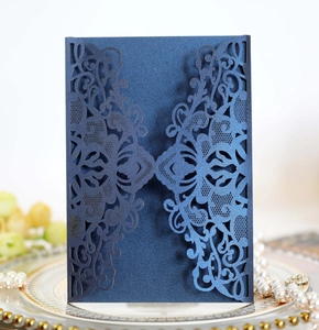 Close-up of navy blue laser-cut floral invitation card on elegant porcelain plate