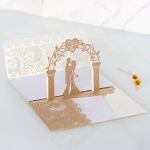 Detail of 3D laser cut wedding invitation with gold glitter and couple silhouette