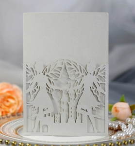 Macro shot of laser-cut fairy wings and castle detail on white pearlescent invitation card