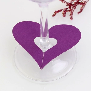Macro view of purple heart-shaped paper place card with hollow design on wine glass