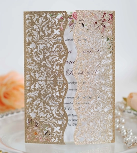 Macro detail of laser-cut gold glitter wedding invitation with elegant floral hollow design