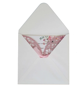 Detail of pink laser-cut wedding invitation with glitter finish and silk ribbon bow
