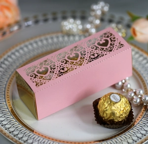 Detail of pink laser-cut wedding candy box with heart pattern and golden mirror finish