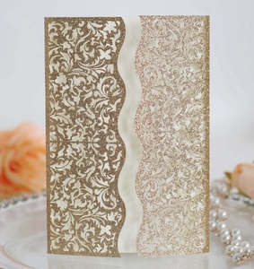 Detail of luxury gold glitter laser cut invitation cover with intricate vine patterns