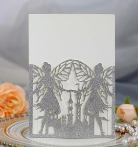 Close-up of laser-cut silver glitter invitation featuring fairy wings and castle silhouette