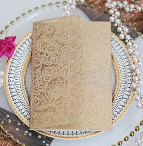Detailed laser-cut lace floral pattern on champagne gold glitter wedding invitation