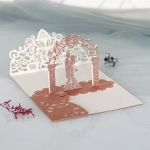 Détail macro d'une carte de mariage découpée au laser avec paillettes or rose et couple