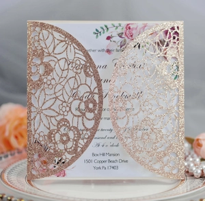 Close-up of laser cut floral wedding invitation in rose gold glitter paper with floral inlay