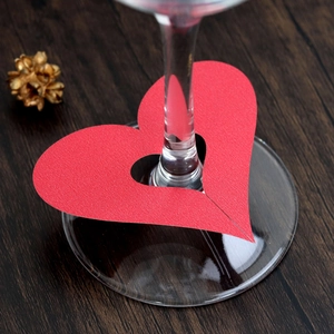 Close-up of heart-shaped red paper glass cards with cross-cut on a wooden table